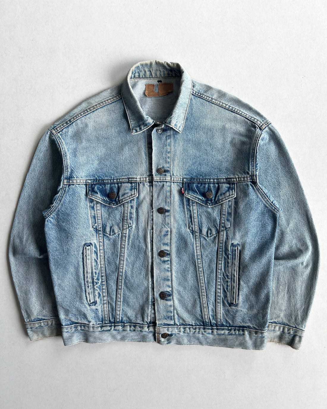 Faded blue denim trucker jacket with a pointed collar, metal buttons and chest pockets